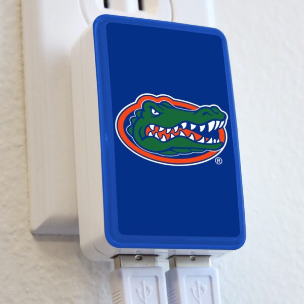 A QuikVolt Florida Gators WP-200X Classic Dual-Port USB Wall Charger featuring the university of florida gators logo in a wall outlet, with two plugged in cords below.