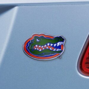 A colorful Florida Gators Sports Grip Steering Wheel Cover affixed to a blue car, displaying a stylized, fierce-looking alligator in green with red and blue accents.