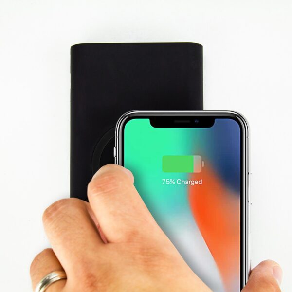 A person's hand holding an Florida Gators 8000WX Wireless Mobile Charger - Qi Certified showing 75% battery status next to a black wireless charger on a white background.