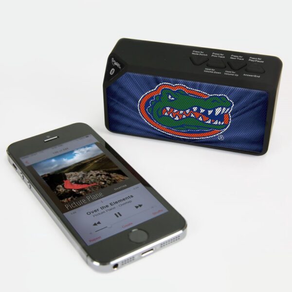Smartphone displaying a music player app next to a Florida Gators BX-100 Bluetooth Speaker with a colorful alligator design on a white background.