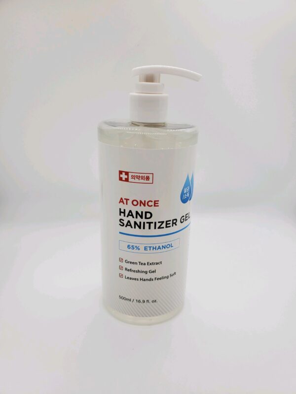 A bottle of At One 16oz Hand Sanitizer with a pump dispenser, containing 65% ethanol and green tea extract, on a white background.