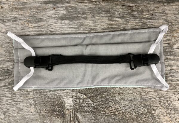 Gray adjustable ELASTIC MASK CLIP EXTENDER 5/Pack with white straps and a black plastic buckle, placed on a rustic wooden surface.