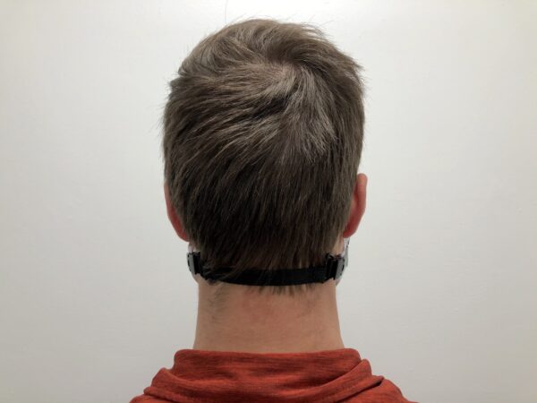 Rear view of a person with short brown hair wearing an ELASTIC MASK CLIP EXTENDER 5/Pack around their neck, standing against a plain white background.