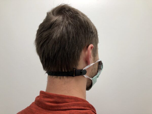 Man wearing a ELASTIC MASK CLIP EXTENDER 5/Pack with a strap around the back of his head, viewed from the side against a plain white background.