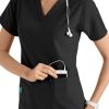 A smiling healthcare professional in a CROSS FLEX V-NECK MEDIA SCRUB TOP C12110 with a stethoscope around her neck, inserting a device into her pocket.