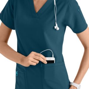 Nurse in CROSS FLEX V-NECK MEDIA SCRUB TOP C12110 using smartphone with stethoscope around neck, smiling and looking to her side.
