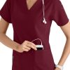A smiling healthcare worker in a CROSS FLEX V-NECK MEDIA SCRUB TOP C12110 uniform using a mobile device with headphones attached.