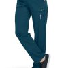 A person wearing teal medical scrub FLAT FRONT STRAIGHT LEG PANT C52106 and black sneakers, with a hand resting on the hip and the focus on the pants pocket details.