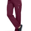 Woman wearing FLAT FRONT STRAIGHT LEG PANT C52106 medical scrubs with multiple pockets and black sneakers, standing in a profile pose showcasing the garment.