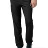 Close-up of black CARHARTT C55106 - MEN'S ATHLETIC CARGO PANT and teal sneakers worn by a person standing with one hand partially tucked in a pocket.