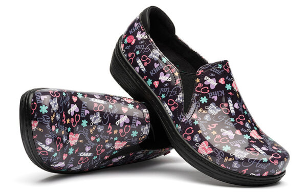 A pair of Moxy by Klogs Footwear nursing shoes with a black background adorned with colorful medical symbols and words like "care" and "heart.