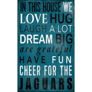 Jacksonville Jaguars Football and My Dog Sign with text "in this house we love, hug, laugh a lot, dream big, are grateful, have fun, cheer for the jaguars" on a blue wooden background.