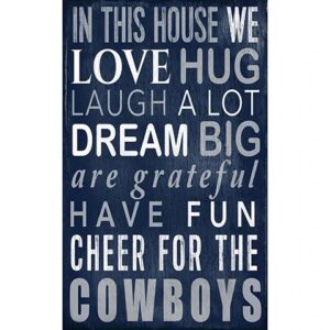 Decorative wall art with text on a blue wooden background listing positive phrases like "love, hug, laugh a lot, dream big" and "cheer for the cowboys.