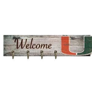 Rustic "welcome" sign with distressed wood background and four metal hooks, featuring red and green lettering.
