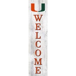Vertical "welcome" sign with a serif font, featuring a green and orange letter "u" at the top, set against a white wooden plank background.