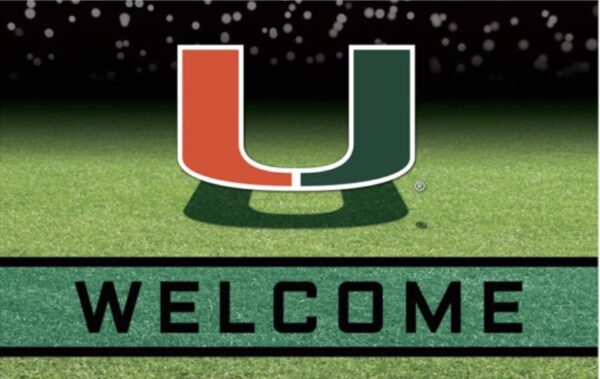 Miami Hurricanes Crumb Rubber Door Mat featuring a green and orange "u" above a "welcome" sign, set against a backdrop of a grass field with a blurred stadium in the distance.