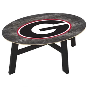 Oval coffee table with a distressed wood finish and a black and red "g" logo emblem centered on the tabletop, supported by black legs.