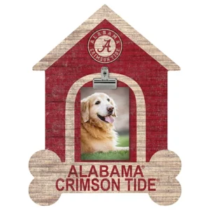 A golden retriever smiling in a wooden alabama crimson tide themed photo frame shaped like a doghouse.