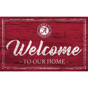 A wooden sign featuring the text "welcome to our home" with an alabama crimson tide logo on red painted background.