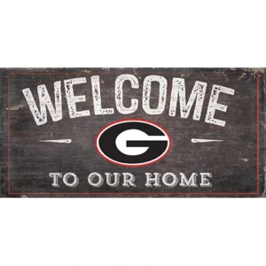 Rustic 'welcome to our home' sign featuring a black oval with a white 'g' in the center, exhibited on a weathered wooden background.