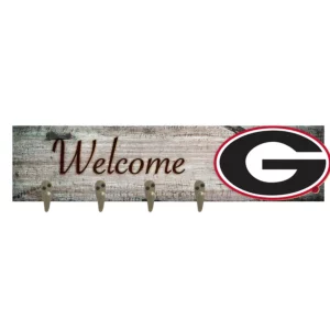 A weathered wooden "welcome" sign with four hooks and a prominent black and red 'g' logo on the right.