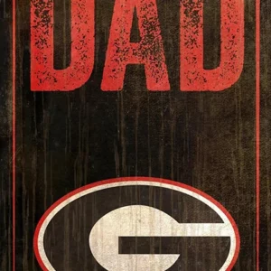 A vintage-style decorative sign reading "best dad" with a weathered georgia bulldogs logo in an oval, all against a dark, distressed wooden background.