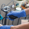 A healthcare professional in blue AMMEX Exam Blue Nitrile PF Disposable gloves measuring a patient's blood pressure with a sphygmomanometer.