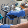 A healthcare worker in AMMEX Professional Cerulean Nitrile PF Exam Gloves measures a patient's blood pressure using a sphygmomanometer.