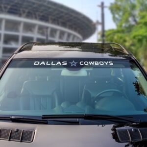 Car windshield with a Dallas Cowboys Windshield Decal, parked with blurred trees and a building in the background.
